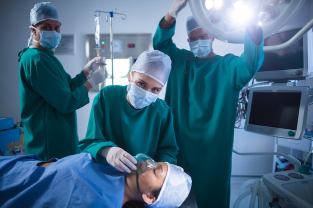 Surgeons adjusting oxygen mask on patient mouth in operation theater