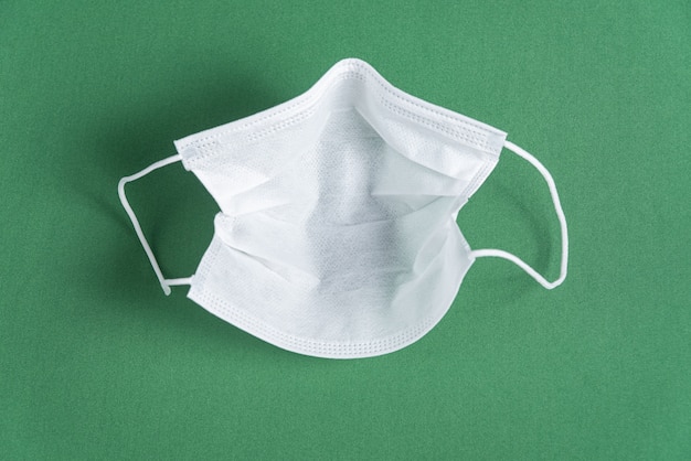 Surgical mask over minimalist green background