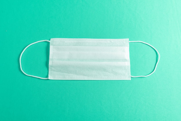 Surgical mask over minimalist green background