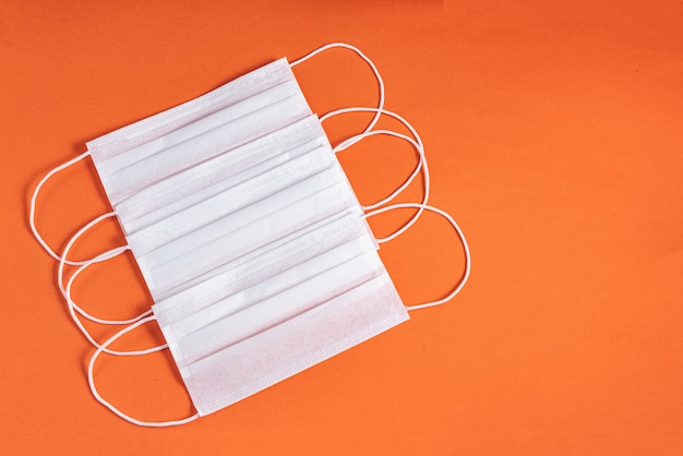 Surgical mask over minimalist orange background