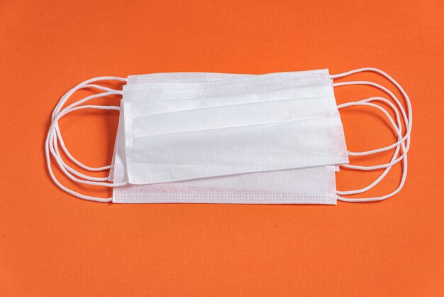 Surgical mask over minimalist orange background