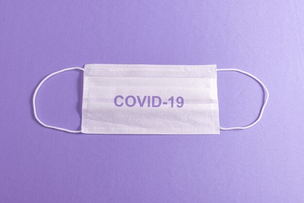 Surgical mask over minimalist purple background