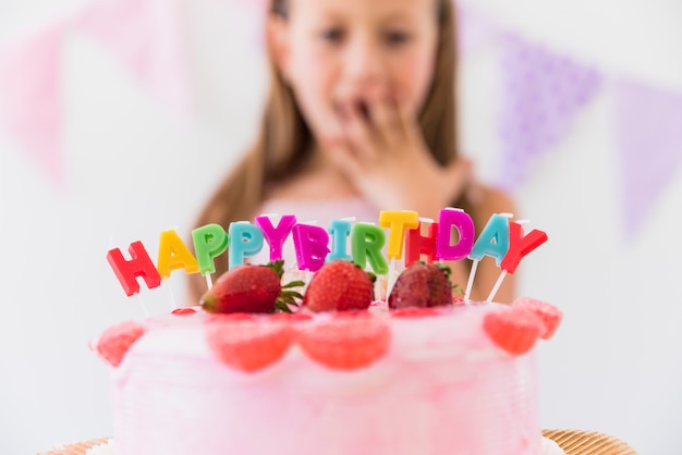 Surprise cute girl behind delicious strawberry birthday cake