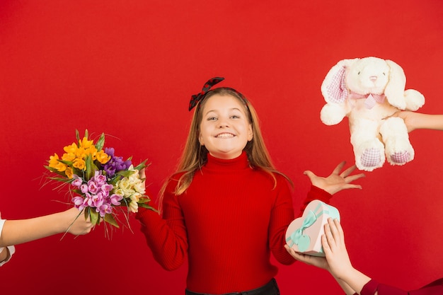 Surprised and astonished. Valentine's day celebration. Happy, cute caucasian girl isolated on red studio background. Concept of human emotions, facial expression, love, relations, romantic holidays.