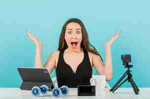 Free photo surprised blogger is posing at camera by raising up her hands on blue background