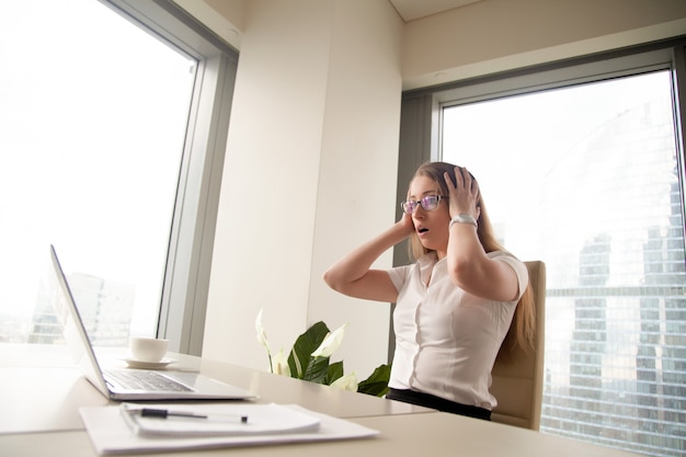 Free Photo surprised businesswoman sitting with head in hands