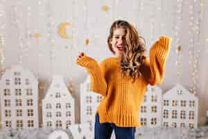 Free photo surprised, cheerful girl happily laughs in cozy new year's atmosphere, posing for portrait in knitted sweater over size