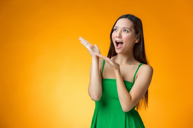 The surprised Chinese girl on yellow background