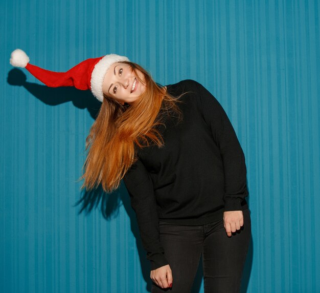 surprised christmas girl wearing a santa hat on the blue studio background