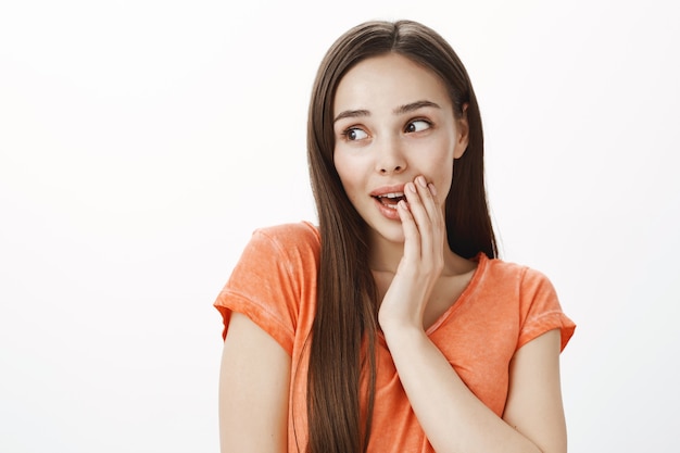 Surprised coquettish young woman chuckling and looking aside, gossiping about someone