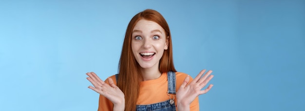 Free photo surprised delighted happy friendlylooking amused redhead female friend learn incredible good news congratulating girlfriend fascinated wide eyes camera joyfully clap hands amazed blue background