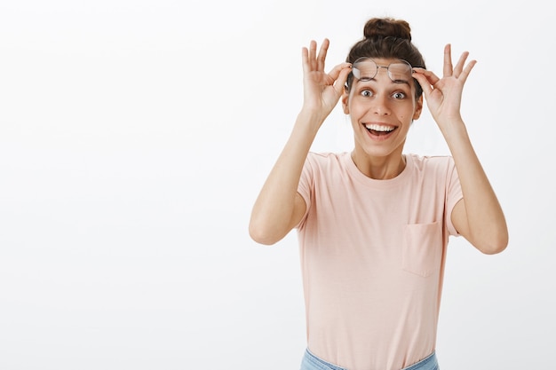 Surprised and excited girl with glasses posing against the white wall