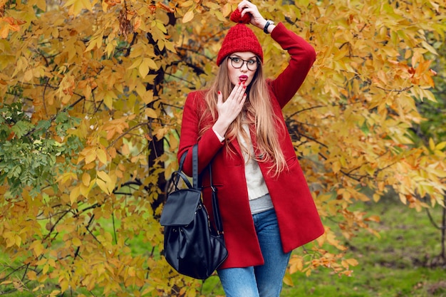 Surprised face. Autumn park. Pretty young  lady walking and enjoying nature.