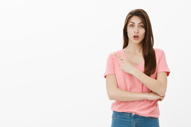 Surprised girl looking amazed and pointing upper left corner