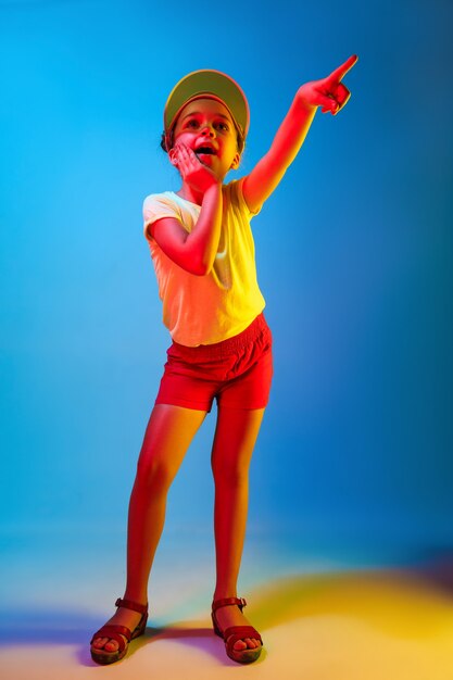 Surprised girl pointing isolated on blue wall