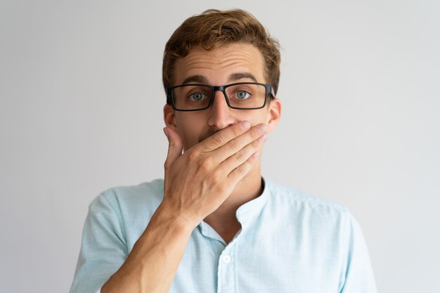 Free photo surprised guy in glasses learning unexpected news or shocking gossip.