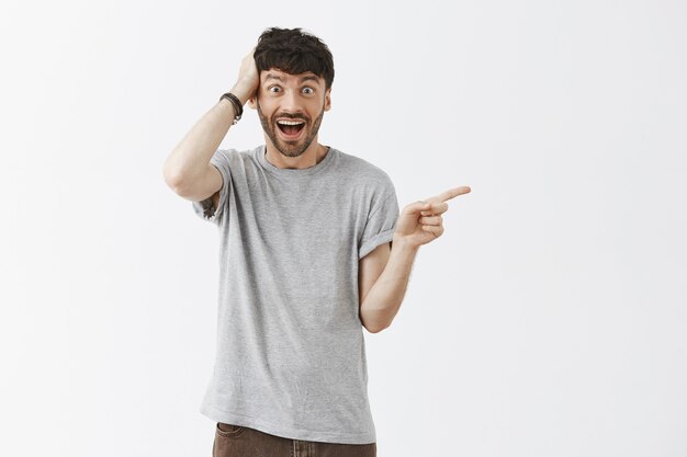 Surprised handsome guy posing against the white wall