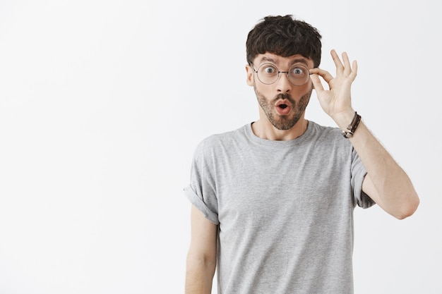 Surprised handsome guy posing against the white wall