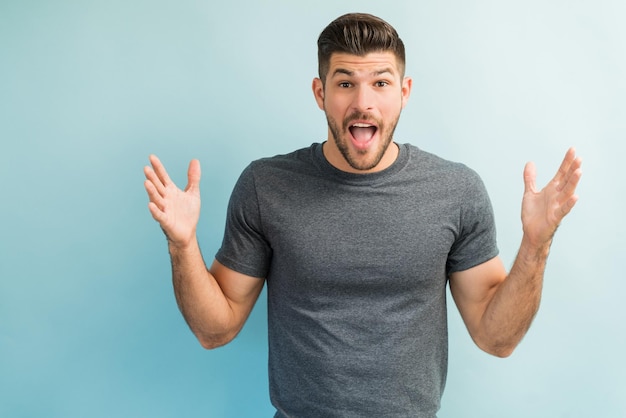 Surprised male gesturing while standing with mouth open  in studio