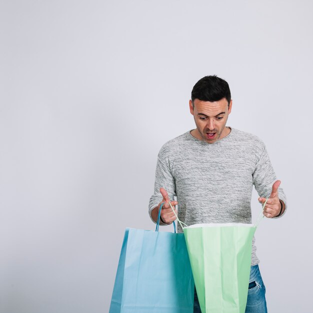 Surprised man looking into shopping bag