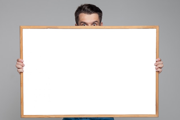 Free photo surprised man showing empty white board