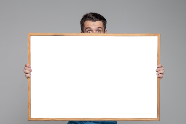 Free photo surprised man showing empty white board