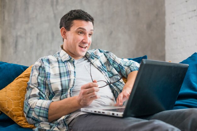 Surprised man using laptop on sofa 