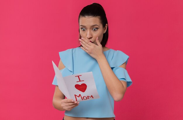 Surprised pretty young woman reading letter from her child 