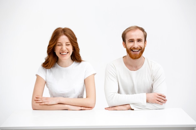 Free photo surprised redhead girl and boy sitting at white desk with