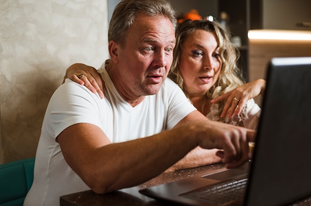 Surprised senior couple looking at laptop