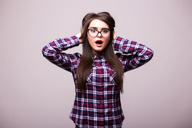 Surprised shocked young woman standing with opened mouth over isolated grey background