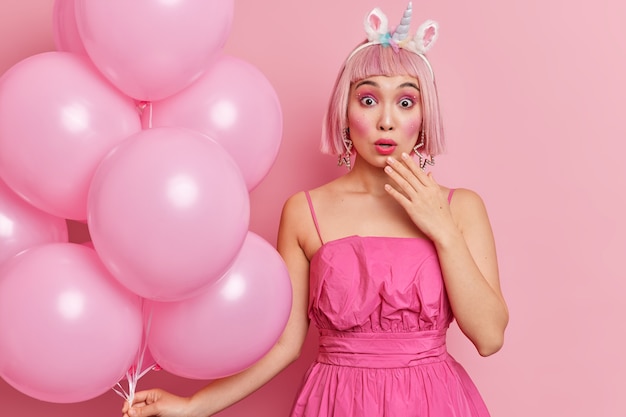 Surprised teenage girl with pink hair stares shocked at camera