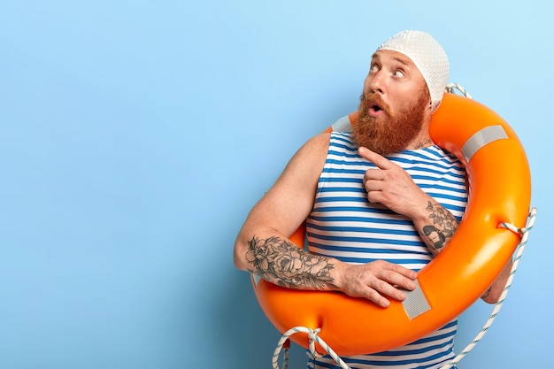 Free photo surprised unshaven male vacationist dressed in bathingcap and striped vest