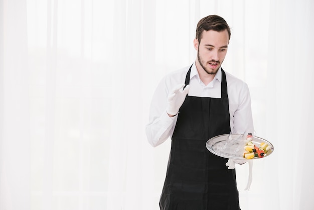 Free photo surprised waiter holding plate