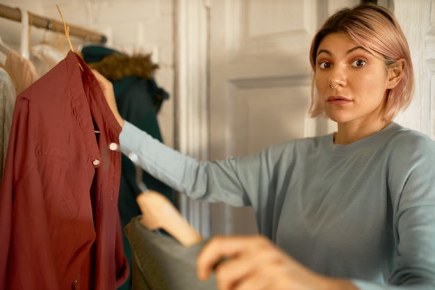 Free photo surprised woman gets clothes from washing machine centre.