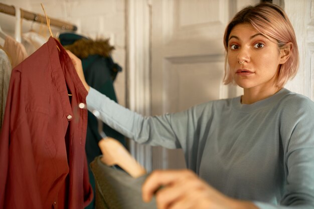 Surprised woman gets clothes from washing machine centre.