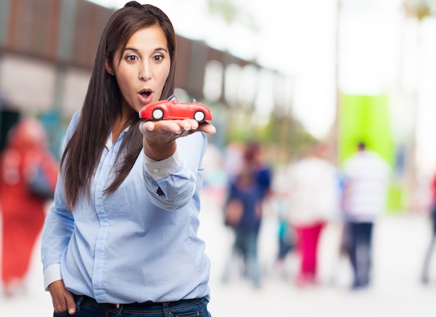 Surprised woman holding a red car