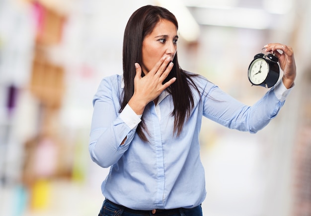 Surprised woman looking at an alarm clock