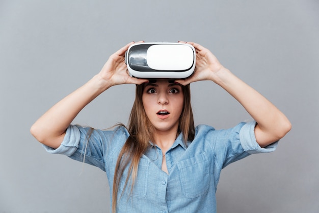 Surprised Woman in shirt takes off virtual reality device