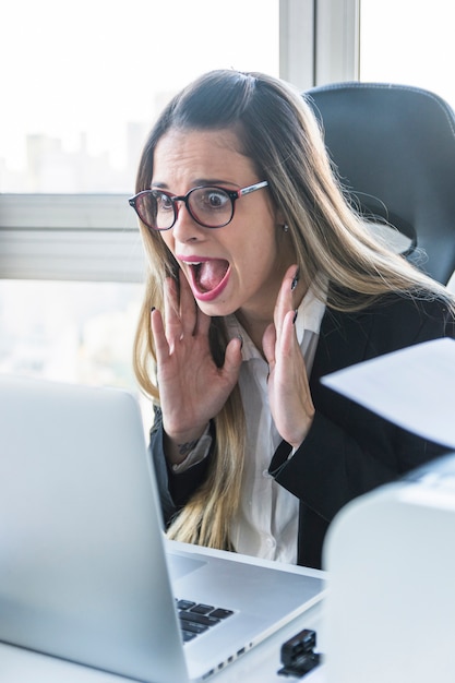 Surprised young businesswoman looking at laptop in the office