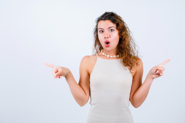 Surprised young girl is looking at camera by pointing right and left with forefinegrs on white background