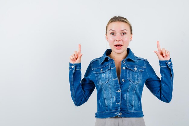 Surprised young girl showing the top with her fingers on white background