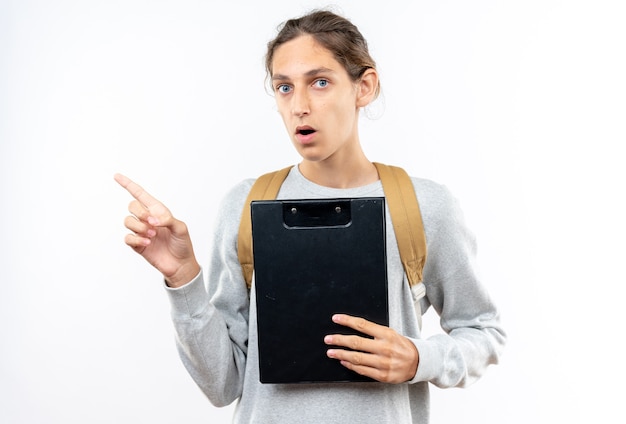 Free Photo surprised young guy student wearing backpack holding clipboard points at side