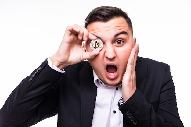 Free photo surprised young man on white holds bitcoin coin in his hands