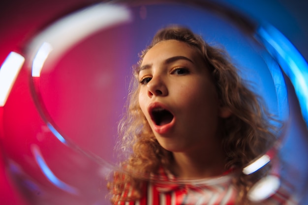 Free photo surprised young woman in party clothes posing with glass of wine. emotional female cute face. view from the glass