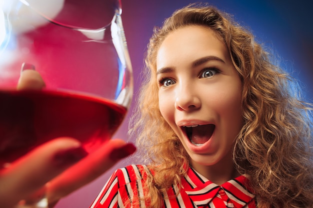 Free Photo the surprised young woman in party clothes posing with glass of wine.