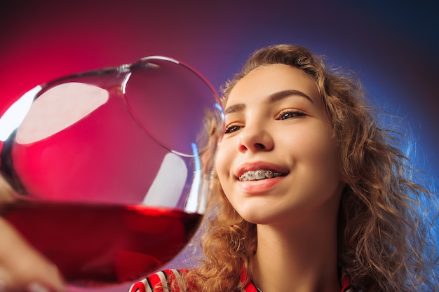 Free Photo surprised young woman in party clothes posing with glass of wine