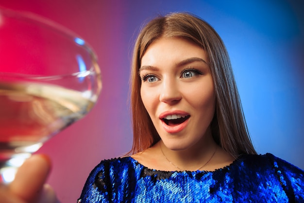 surprised young woman in party clothes posing with glass of wine