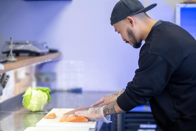 Sushi cafe. Sushi chef cutting fish and making sushi