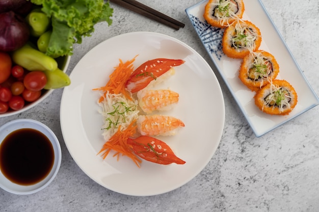 Free Photo sushi is in a plate with chopsticks and dipping sauce on a white cement floor.